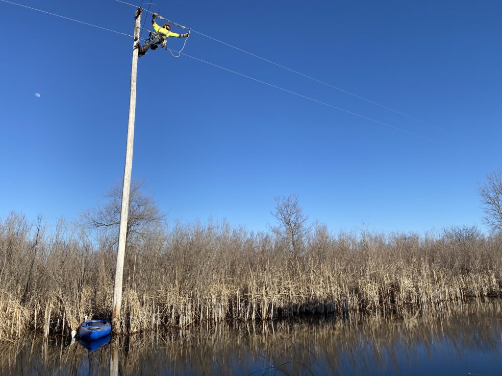 MCPA employee making repairs on a pole that is surrounded by water
